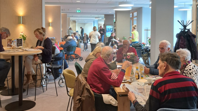 Een afbeelding van De Basis waar mensen gezellig een kopje koffie drinken.